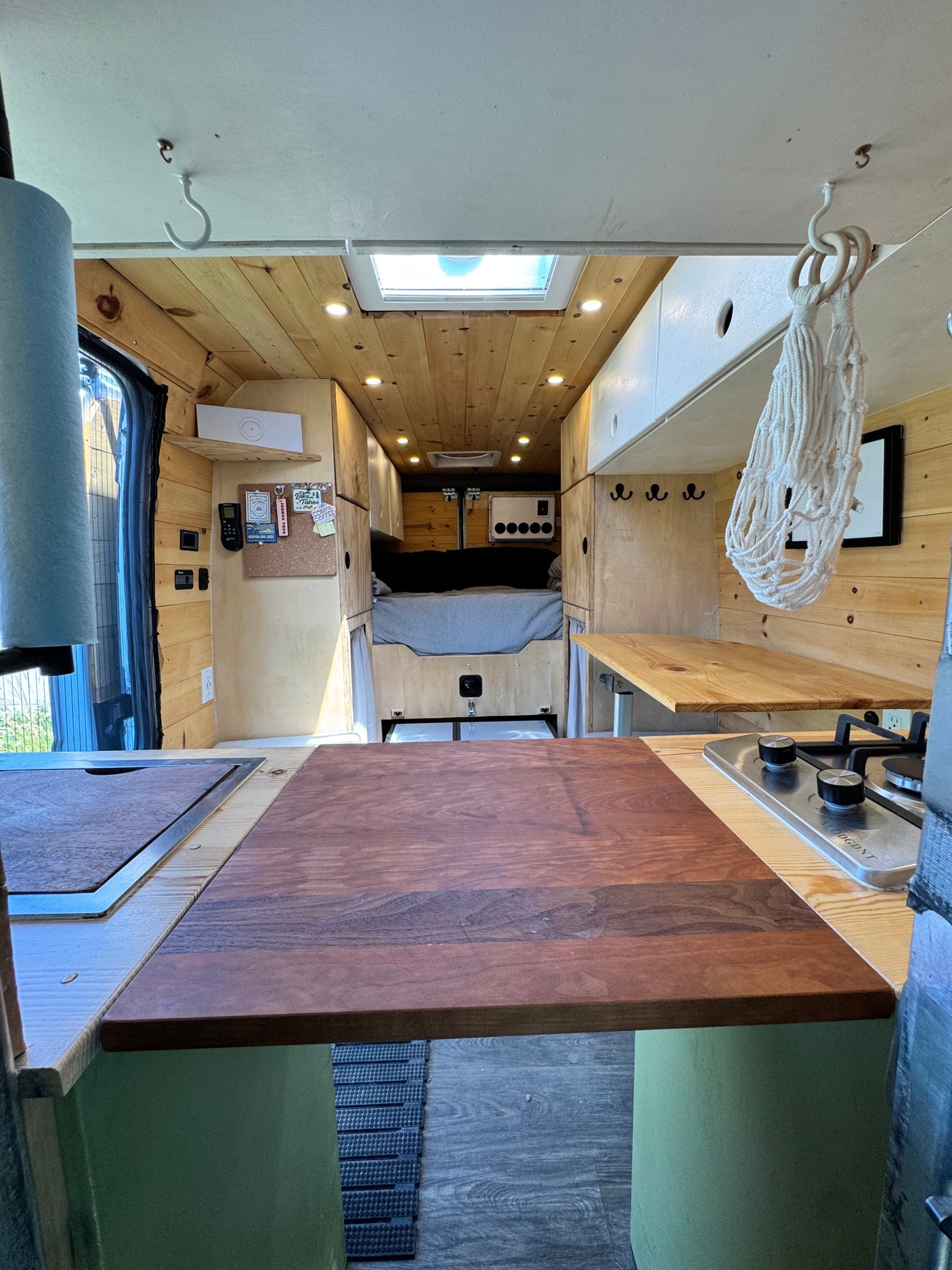 Spacious, wood-paneled camper van interior shows kitchen, bed, and skylight. An excellent option for rv rental adventures.