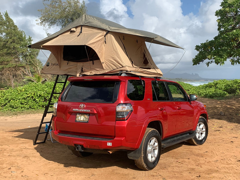 A red Toyota 4Runner with a tan rooftop tent and ladder, parked on a dirt path overlooking the ocean. Great RV rental for beach camping. — photo 7