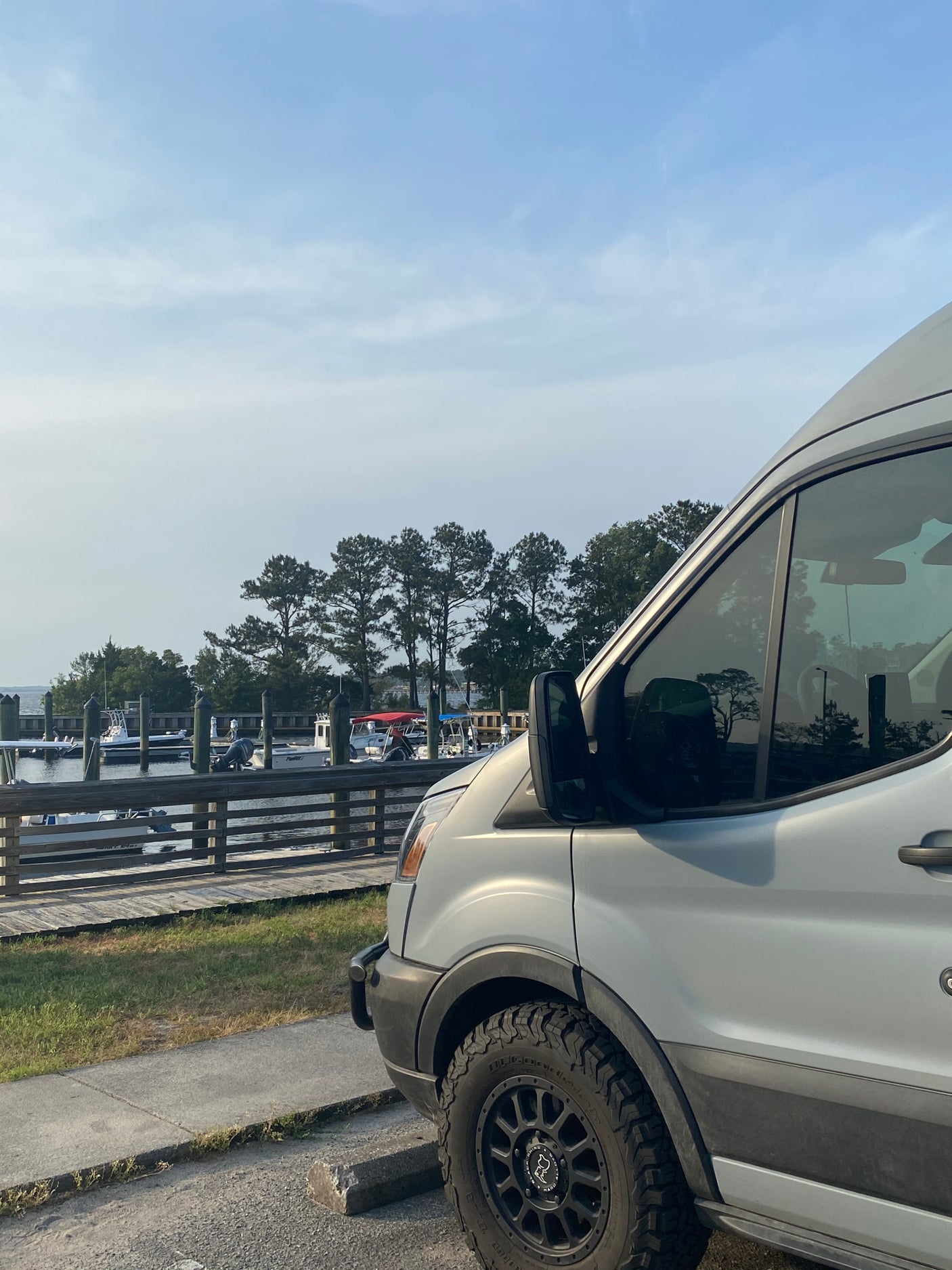 RV rental van beside a serene boat dock, showing its robust tires and the peaceful waterfront scene.