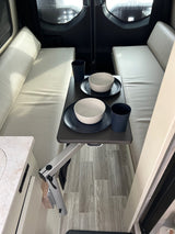 Cozy RV rental dining space: a small table with two place settings positioned between padded bench seats.