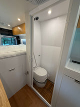 This RV rental offers a compact bathroom with a toilet & shower, a comfortable bed, and smart storage.