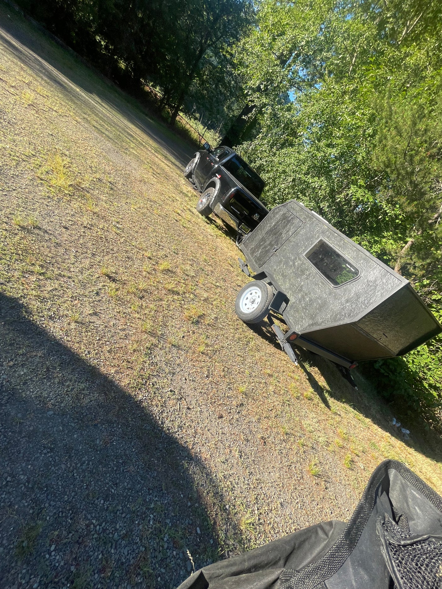 Black pickup truck with a small, rugged travel trailer on a gravel lot, perfect for your next outdoor rv rental trip.
