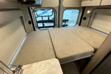 Inside an RV rental camper van: modular bed, rear windows, and side counter with sink. Ready for travel.