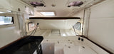 Clean RV rental interior showing a raised bed, compact galley, and white storage compartments.