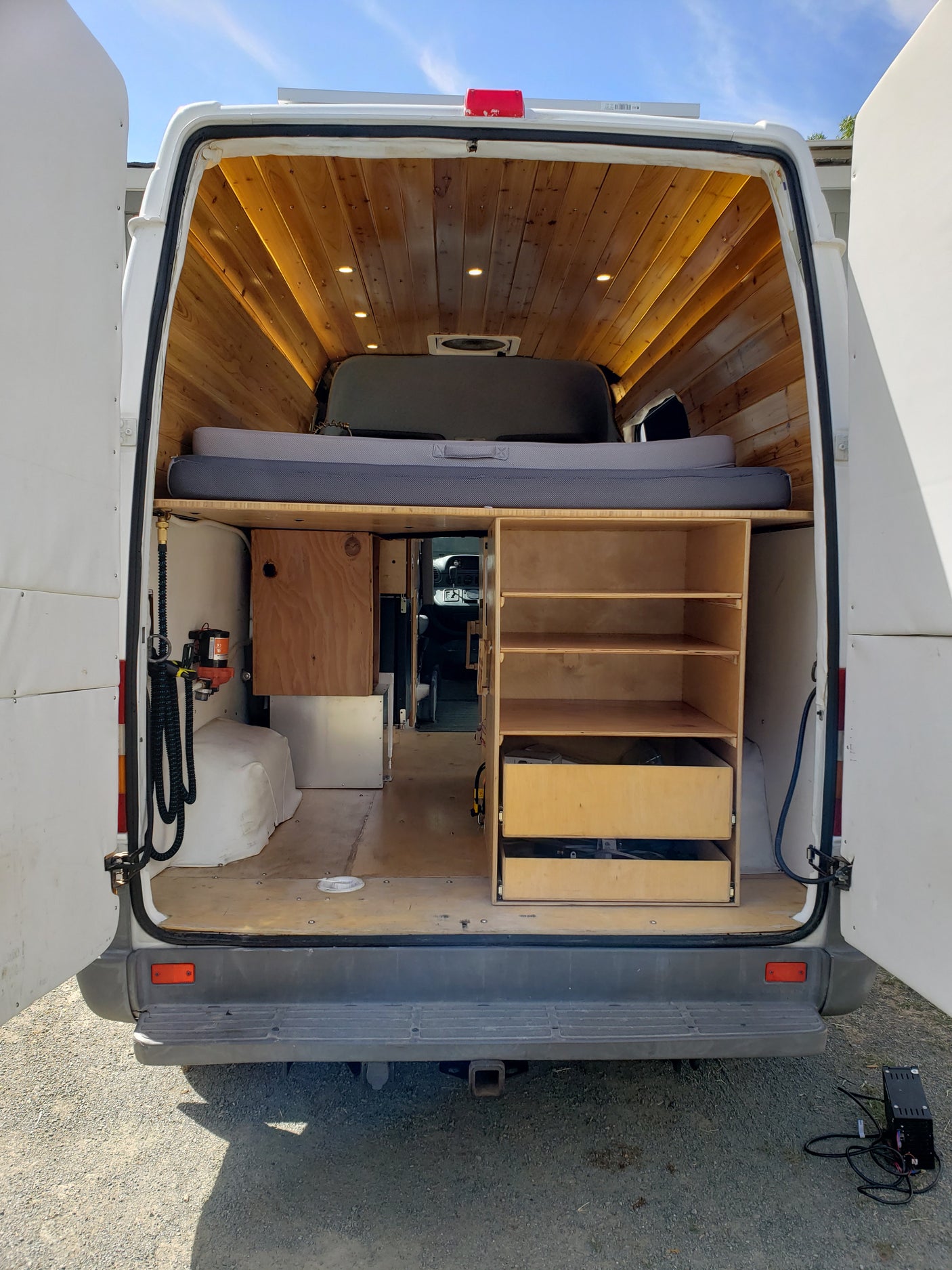 Inside an RV rental van: custom wooden ceiling, bed, and storage shelves. Ready for adventure!