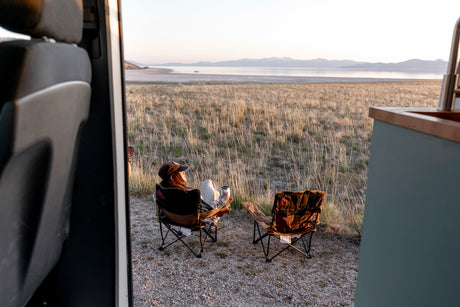 Enjoying the view from an RV rental. Relaxing by a vast lake & mountains at sunset. Perfect for nature lovers!