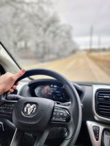 Hand on the Ram steering wheel while driving an RV rental. Dashboard and blurred snowy road visible ahead.