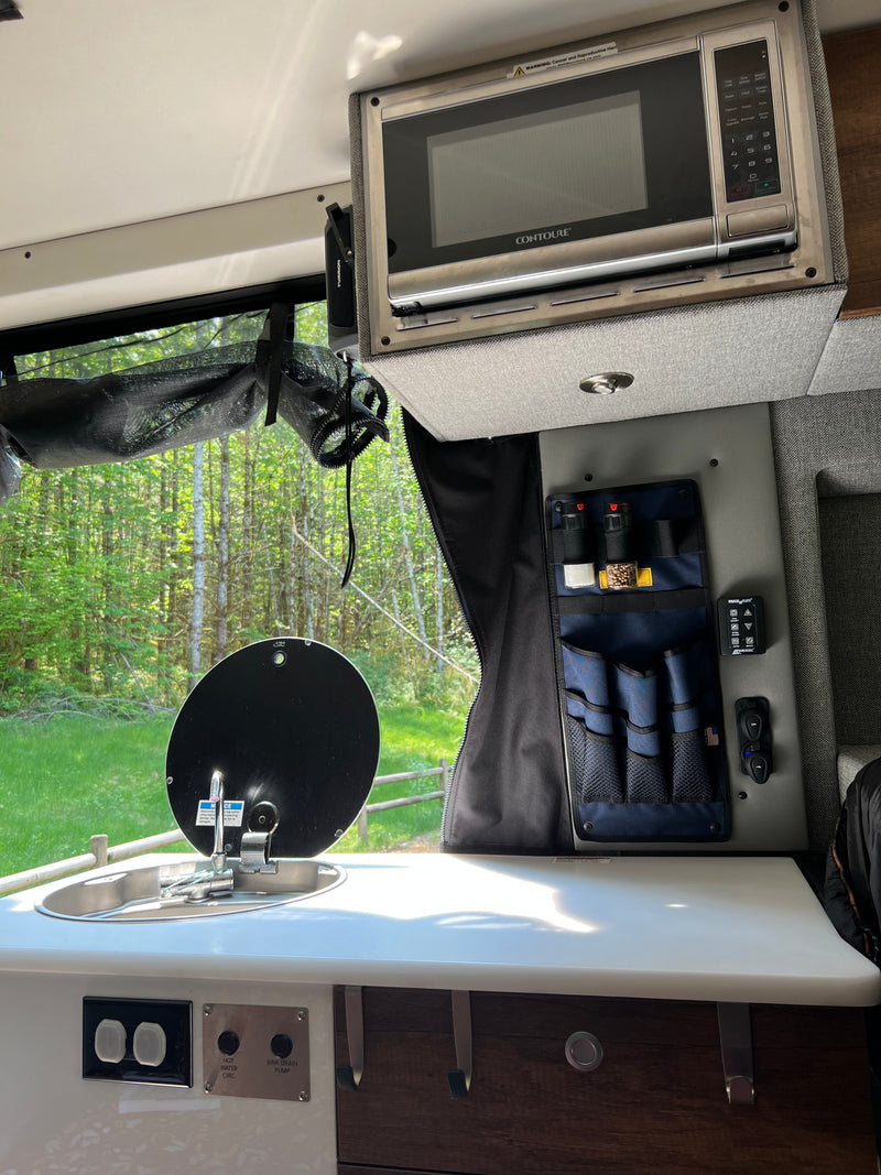 Inside an RV rental: Compact kitchen with a Contoure microwave, sink, & spice storage, enjoying nature views. — photo 18