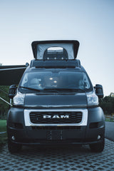 Dark Ram ProMaster camper van, with pop-top open, parked on pavers. Perfect for an rv rental adventure.