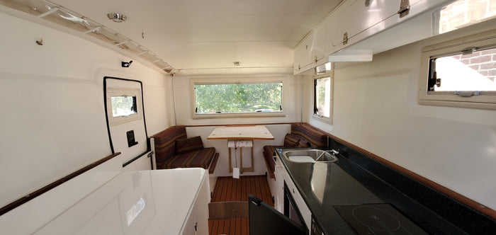  and white storage compartments.|Experience our RV rental: a bright camper interior with a compact kitchen