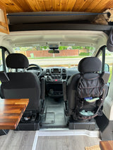 Step inside this RV rental! View of front seats, dashboard, and custom wooden ceiling/storage in a camper van.