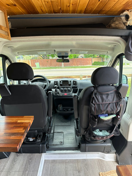 Step inside this RV rental! View of front seats, dashboard, and custom wooden ceiling/storage in a camper van.