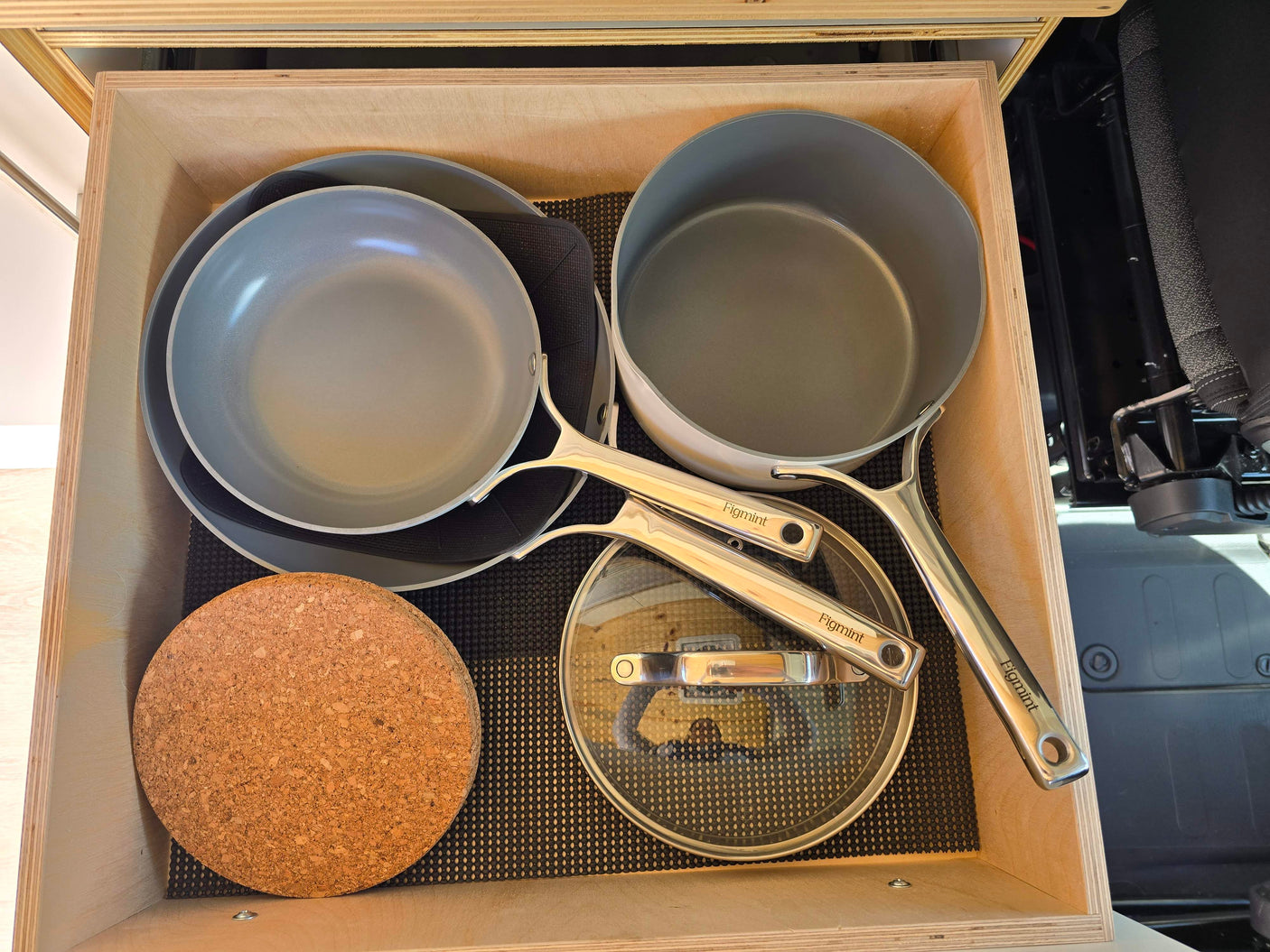 Organized Figmint cooking pans & cork trivet in an RV rental drawer with a non-slip liner.