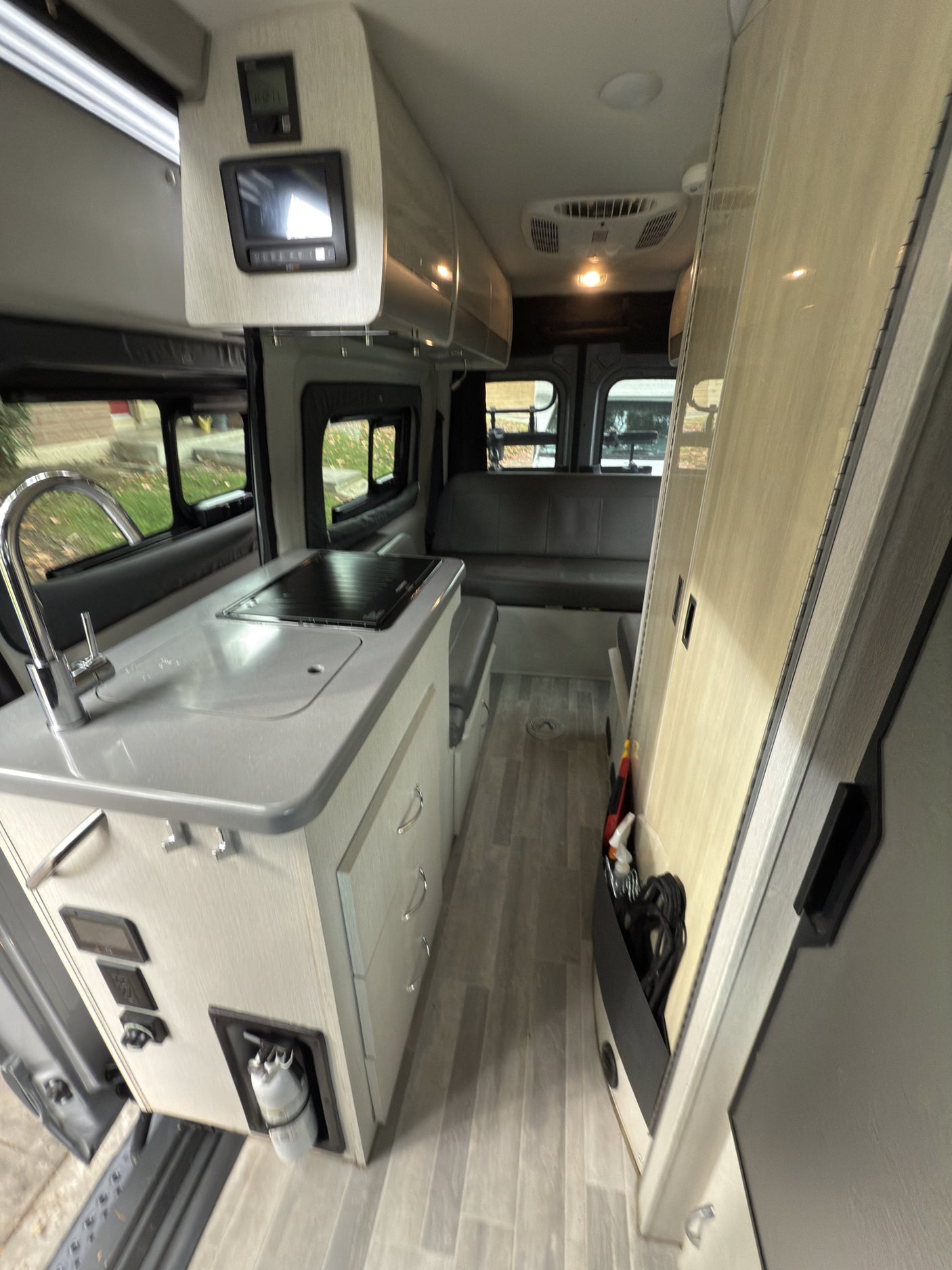 View inside a modern RV rental, featuring a compact kitchen, dinette, and overhead storage in this well-equipped camper.