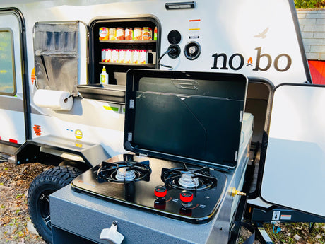 RV rental: Outdoor kitchen with stove, pantry, and paper towel holder for easy camping meals.