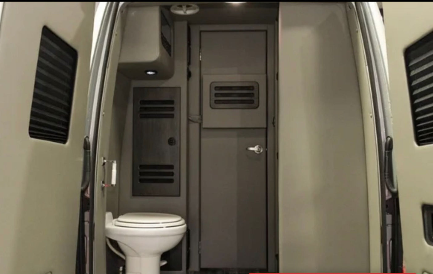 An RV rental's interior from the rear doors, featuring a compact toilet, closed internal door, and ventilation. Practical for travel.