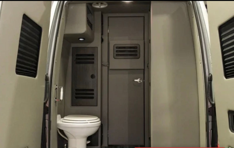 An RV rental's interior from the rear doors, featuring a compact toilet, closed internal door, and ventilation. Practical for travel. — photo 19