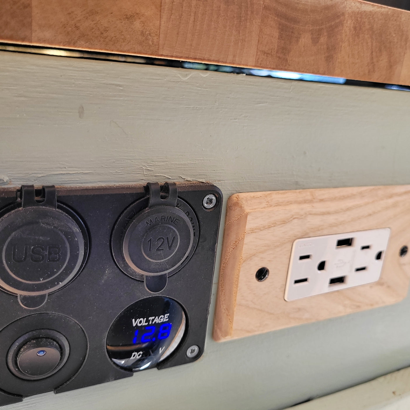 RV rental electrical panel features 12V, USB, AC outlets, and a voltage display for charging and power monitoring.