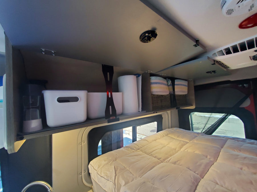 RV rental: Organized overhead shelving with bins & baskets above a cozy bed. Ideal for camper van storage.