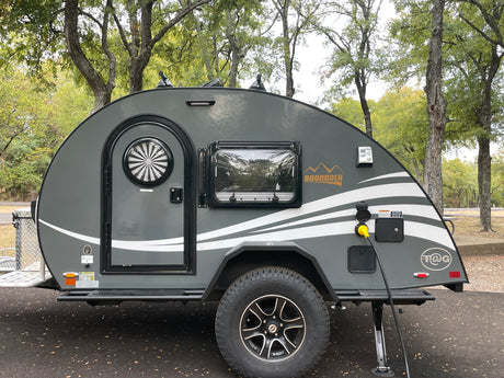 Gray Boondock teardrop **rv rental** parked at a campsite, hooked to power. Ideal for outdoor adventures and travel.