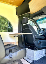 Inside a versatile **rv rental**: swiveling front seat, rear bench, adjustable table, and mounted TV. Perfect for work or leisure.
