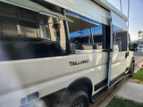 White Tellaro camper van, ideal for rv rental. Side door open, reflections of houses on windows.
