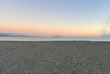 A serene beach at twilight, showcasing a gradient sky of pastels over gentle waves and dark sand. Perfect for an RV rental getaway.