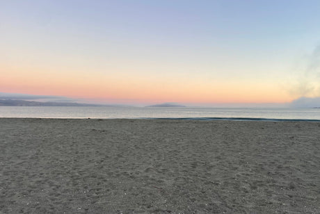 A serene beach at twilight, showcasing a gradient sky of pastels over gentle waves and dark sand. Perfect for an RV rental getaway.