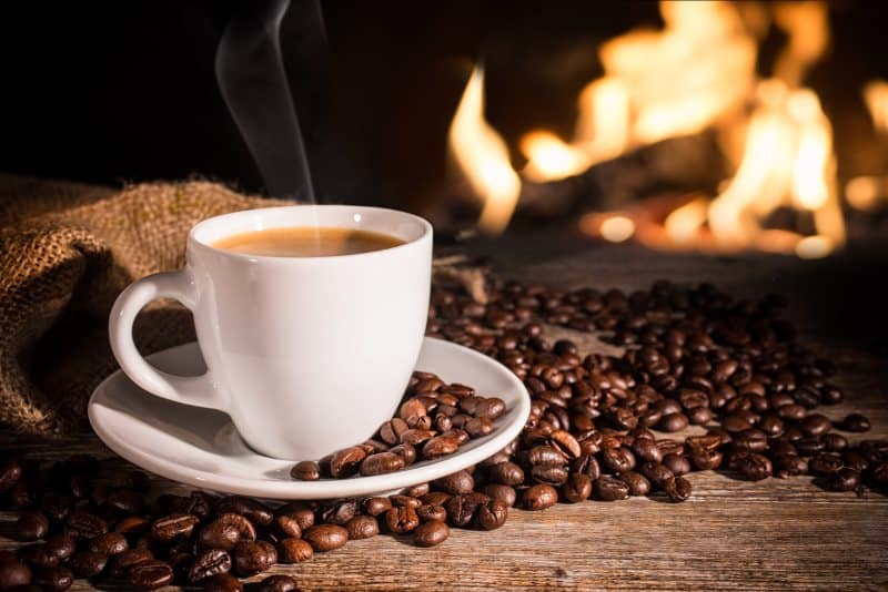 Steaming coffee cup, roasted beans, and fireplace glow – perfect cozy comfort for an RV rental.