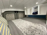 Cozy RV rental bedroom with a comfy bed, overhead storage, and fun cactus window covers.