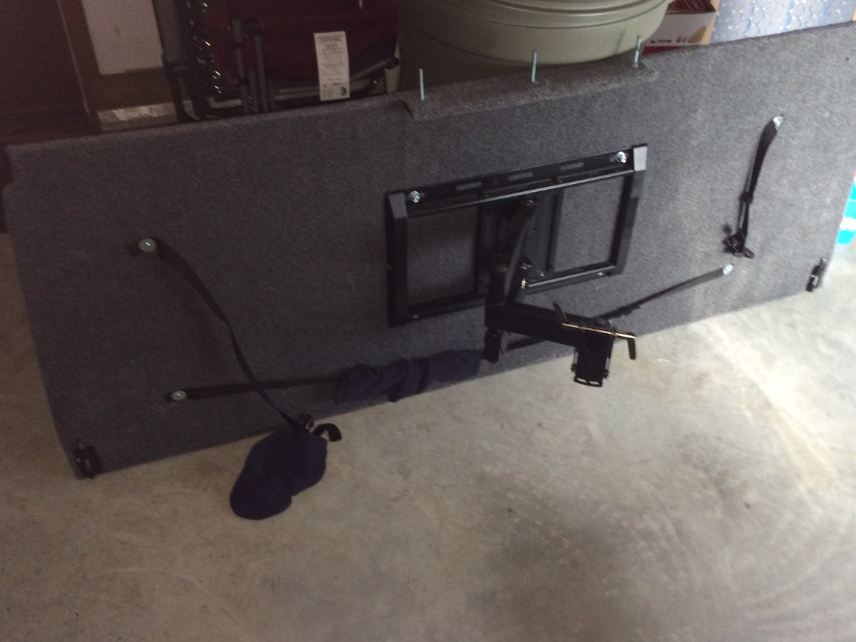 Gray carpeted RV bed panel with a mounted TV bracket and security straps, ideal for RV rental configurations. — photo 8