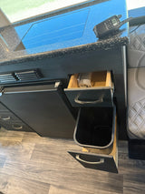 RV rental kitchen featuring a black countertop with a stovetop, radio, refrigerator, and a handy pull-out trash can.