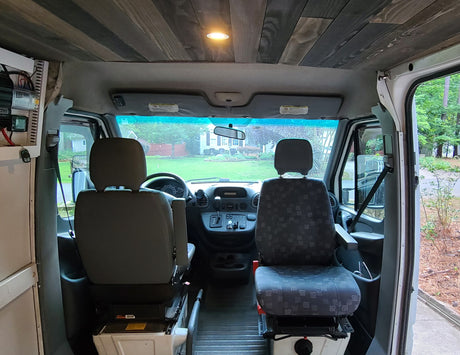 Inside an RV rental's front cabin: custom wood ceiling, comfortable front seats, and dashboard, ready for journeys.