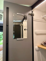 Winnebago rv rental: Grey door with mirror opens to a white interior, likely a shower or closet, with a wood shelf.