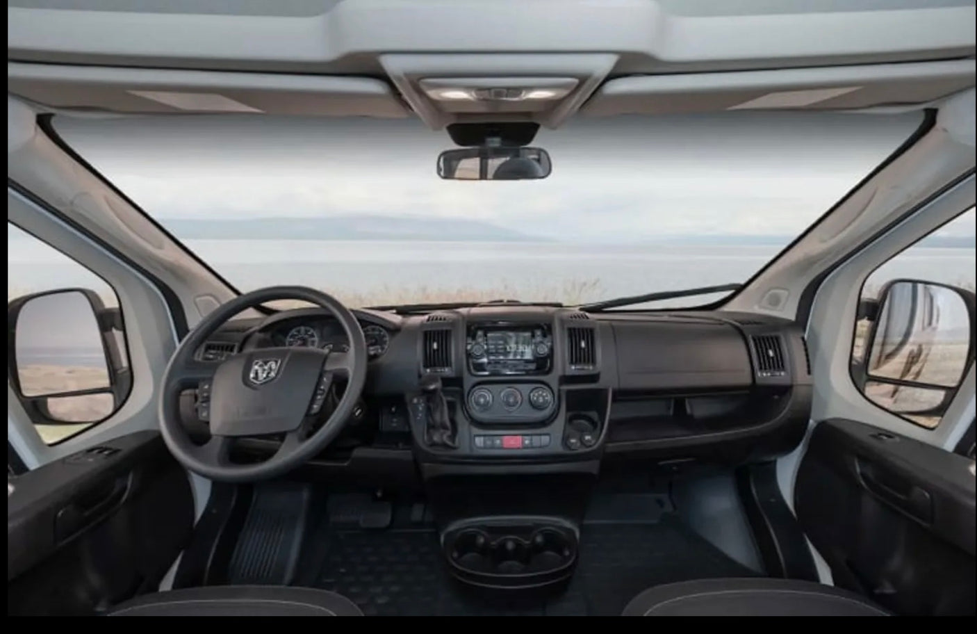View from an RV rental driver's seat, showcasing the dashboard, steering wheel, and a tranquil road trip landscape.
