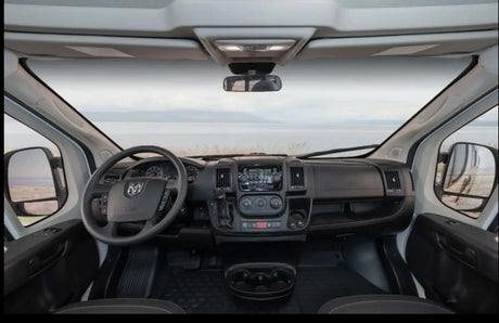 View from an RV rental driver's seat, showcasing the dashboard, steering wheel, and a tranquil road trip landscape.