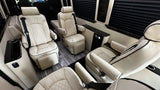 Spacious RV rental interior with cream quilted leather reclining seats, wood-look floor, and privacy blinds for luxurious travel.