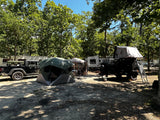 Sunny campsite featuring an RV (perfect for an rv rental), Jeep, camping tent, and overland trailer with rooftop tent.