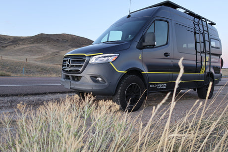 Customized Mercedes Sprinter camper van, perfect for rv rental adventures, parked off-road in a dry, hilly landscape.