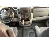 Explore the clean and spacious interior of this RV rental van, showcasing a modern Mercedes dashboard, steering wheel, and robust floor mats.
