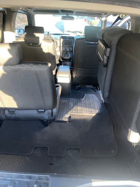 RV rental's spacious interior: black fabric seating, durable patterned floor mats, and a clear view of the front console.