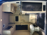 Compact rv rental interior with kitchenette, sink, overhead cabinet, and a portable toilet. Ideal for road trips.