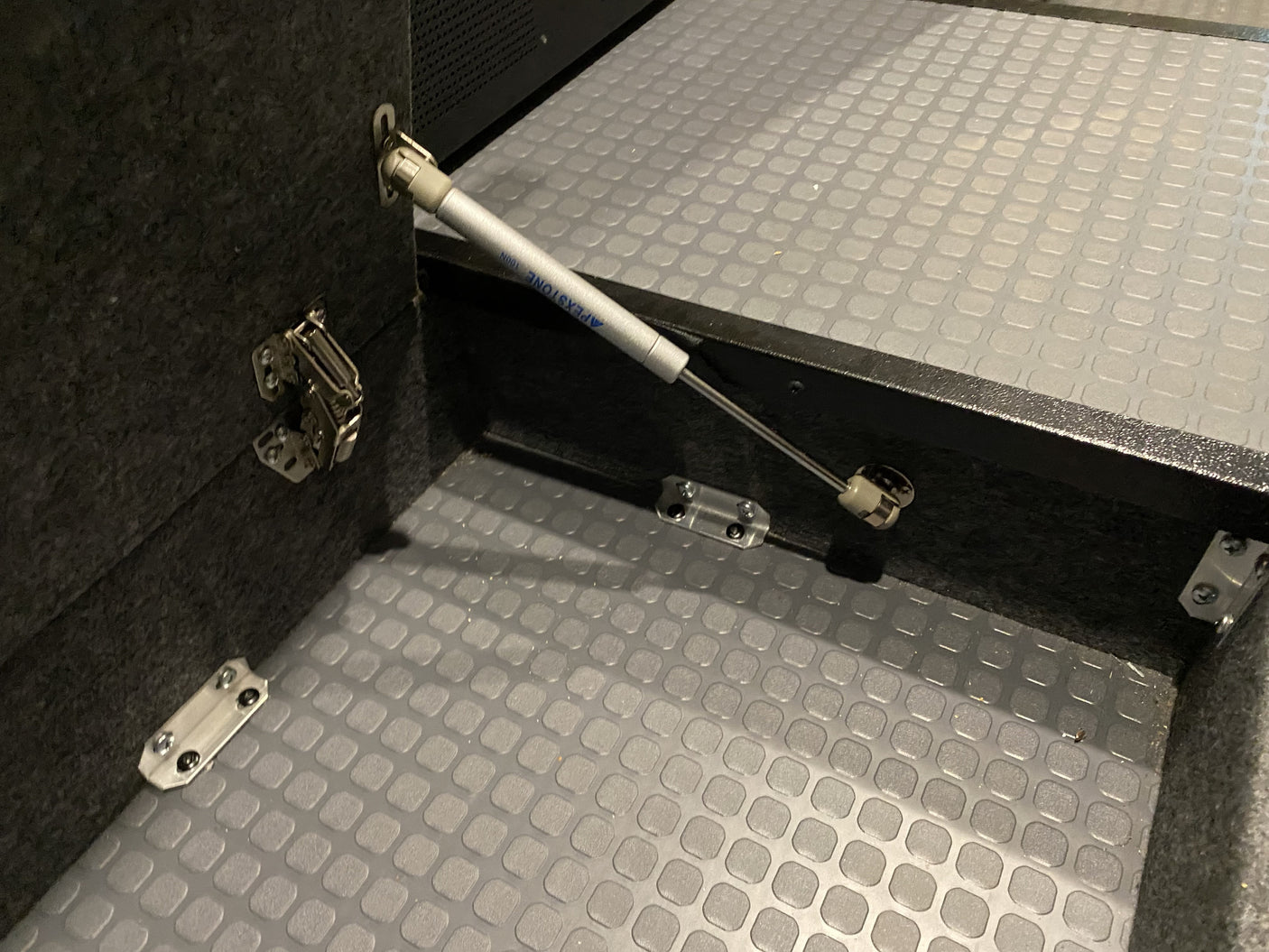 RV rental cabinet showing gas strut lift assist, durable hinges, and textured floor for secure storage.