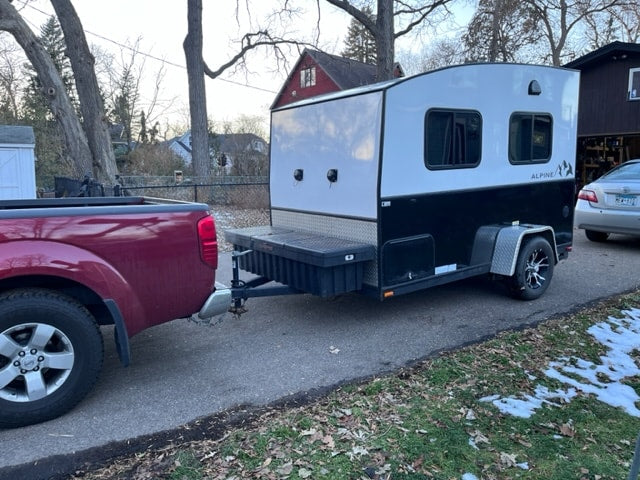 Red pickup truck tows compact, black & white RV rental camper trailer on driveway. — photo 3