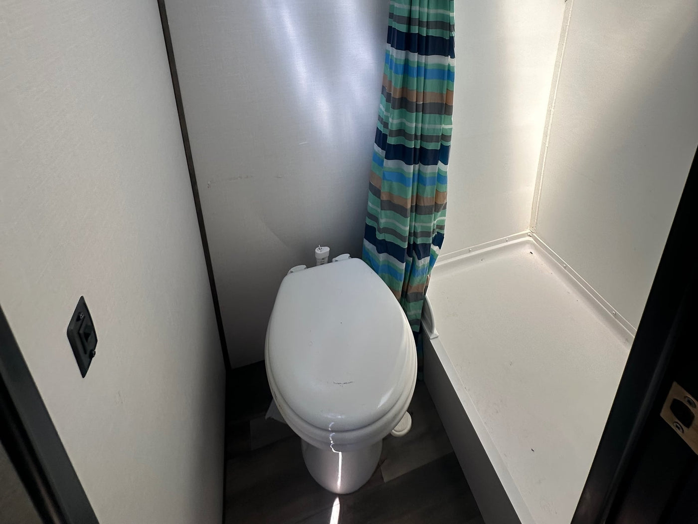 adjacent to a bed with built-in storage.|Compact RV rental bathroom features a toilet — photo 4