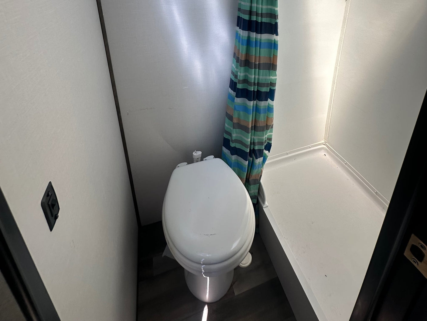  adjacent to a bed with built-in storage.|Compact RV rental bathroom features a toilet
