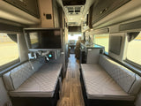 Spacious RV rental interior featuring comfortable upholstered benches, a TV, and kitchenette, perfect for travel.