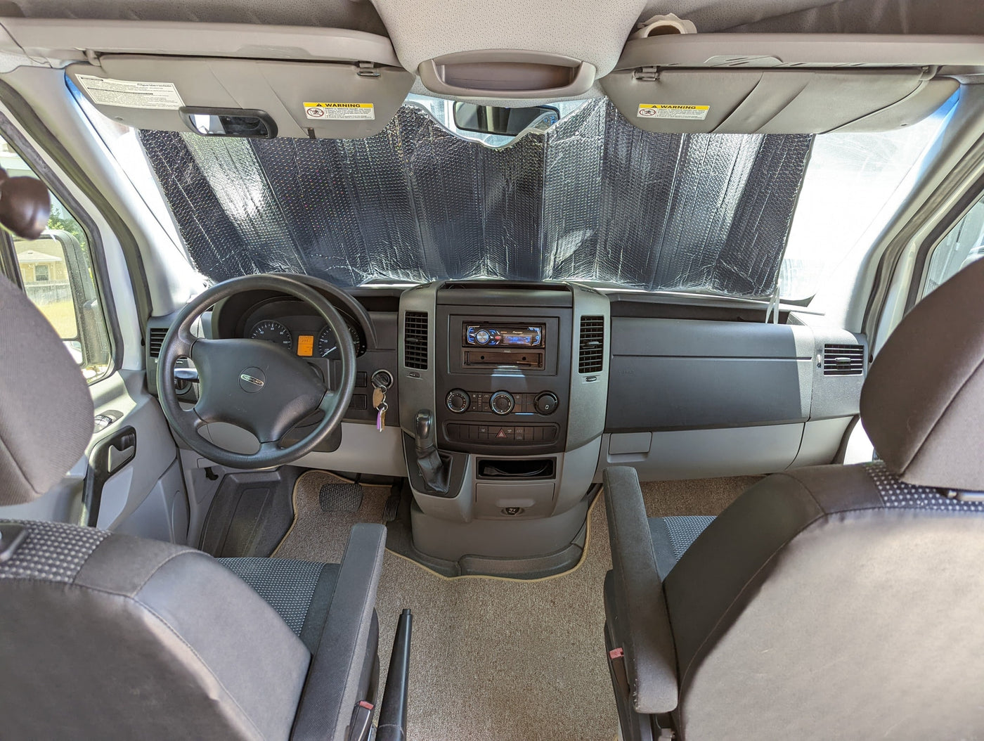 Interior view of an RV rental: driver's cabin with sunshade, dashboard, and seating, ready for travel. — photo 12