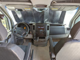 Interior view of an RV rental: driver's cabin with sunshade, dashboard, and seating, ready for travel.