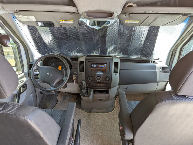Interior view of an RV rental: driver's cabin with sunshade, dashboard, and seating, ready for travel. — photo 12